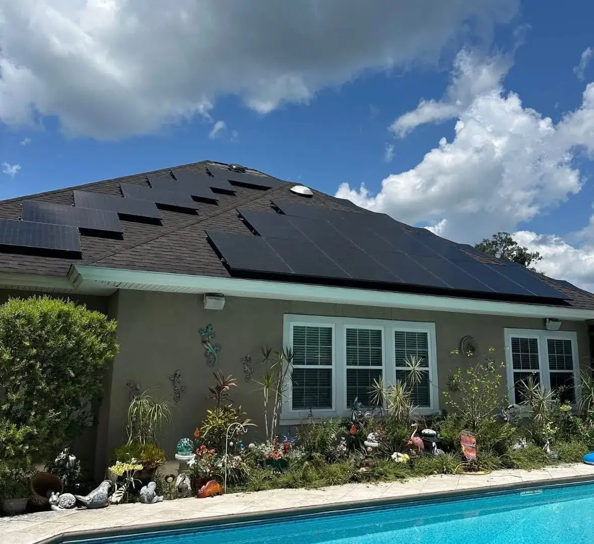 Single-story home with a full black-on-black rooftop solar array beside a pool