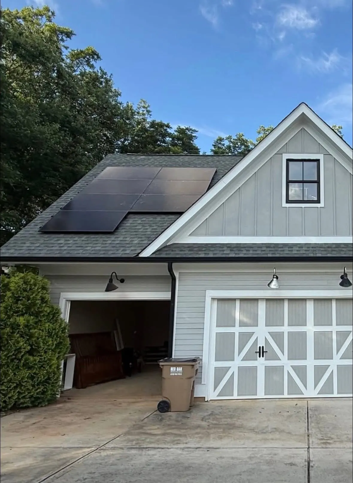 Black solar panels on the roof of a modern farmhouse detached garage