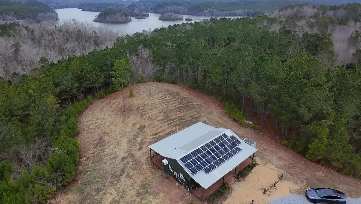 Aerial view of an off-grid cabin above a South Carolina lake with a roof solar array